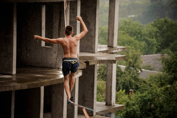 Bir slackline boş bina arka planı üzerinde yürüyen cesur üstsüz gencin arkadan görünüm