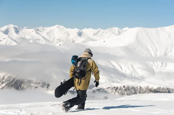 在温暖的滑雪设备的男性登山运动员在雪地上走在他的手滑雪板 — 图库照片