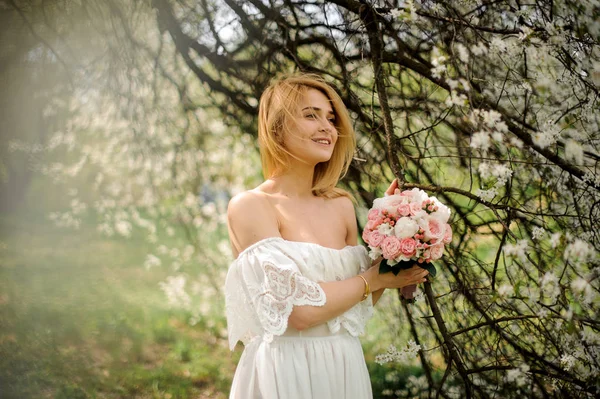 Felice Giovane Donna Bionda Vestito Bianco Con Bouquet Vicino Ciliegio — Foto Stock