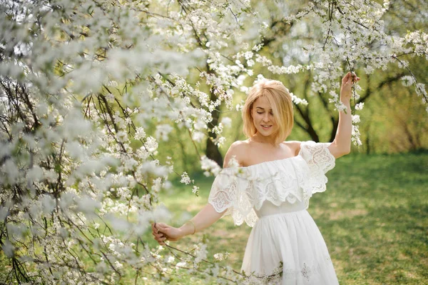 Счастливая Молодая Блондинка Белом Платье Ходит Среди Белых Цветущих Вишневых — стоковое фото