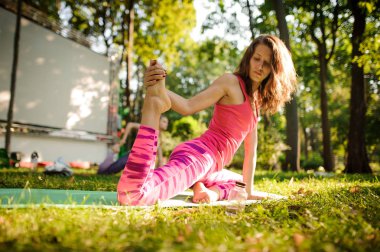 Alt görünümü güzel genç kadının bir parkta çimlerde yoga egzersizleri yapıyor