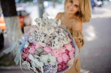 Büyük bir buket peonies gibi çeşitli renkli çiçek tutan gülümseyen sarışın kadın güller vb.