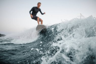 Önalan ile bir adam wakesurfing o aşağı arka planı gri gökyüzü üzerinde bir odak mavi dalga