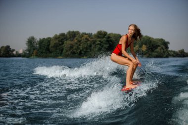 Genç ve güzel sarışın kadın wakesurfer sıcak bir günde mavi sıçramasına dalga sürme