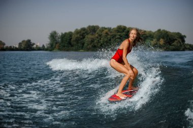 Sıcak bir günde mavi sıçramasına dalga sürme güzel ve ince sarışın kadın wakesurfer