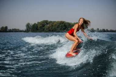 Sıcak bir günde mavi sıçramasına dalga sürme güzel ince sarışın kadın wakesurfer