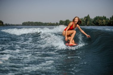 Mutlu ve sıcak bir günde mavi sıçramasına dalga sürme sarışın kadın wakesurfer gülümseyen