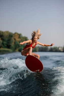 Sarışın genç kadın bir wakeboard mavi su sıcak ve güneşli gün atlama