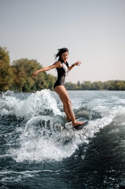 Esmer kadın seksi ve aktif wakesurfing güneşli mavi su aşağı bir gemide