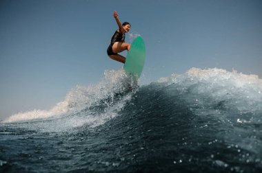 Seksi esmer kadın bir wakeboard yüksek mavi dalga ile atlama güneşli günde su sıçramalarına