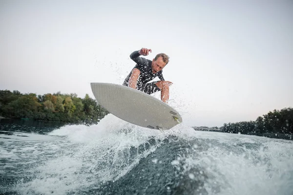 Joven Wakeboarder Traje Baño Saltando Sobre Ola Azul Sobre Fondo —  Fotos de Stock