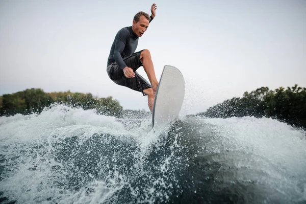 Joven Wakeboarder Traje Baño Saltando Sobre Ola Azul Salpicando Contra —  Fotos de Stock