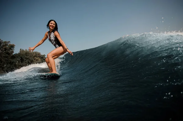 快乐活泼的黑发妇女 Wakesurfing 在蓝色的水在阳光明媚的一天板上 — 图库照片