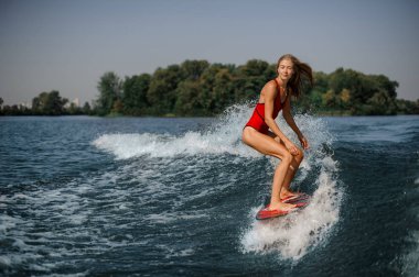 Kırmızı wakeboard bükme diz üzerinde kırmızı mayo duran güzel sarışın kız
