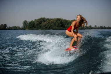 Güzel sarışın kız bükme diz kırmızı wakeboard sürme kırmızı mayo