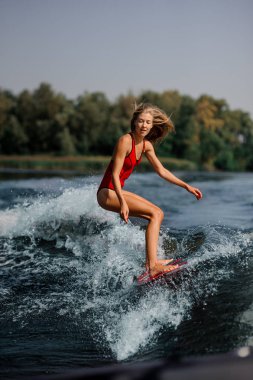Lakeside arka plan üzerinde kırmızı wakeboard sürme kırmızı mayo güzel sarışın kız