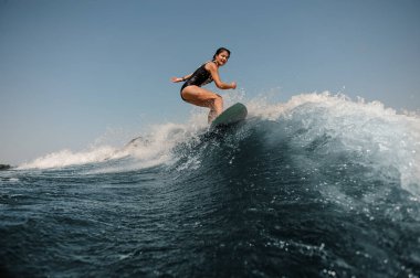 Çekici kız açık bir gökyüzü arka plan üzerinde wakeboard sürme siyah beyaz mayo