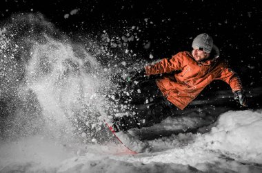 Portakal spor giyim ve geceleri toz karda tahtada atlama genç snowboarder