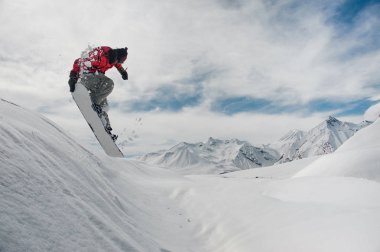 Erkek snowboard snowboard yaparken inanılmaz güzel mavi gökyüzü arka plan üzerinde bir elini tutarak atlama