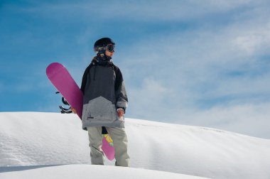 Genç kadın snowboard snowboard dağ ve açık mavi gökyüzü arka plan üzerinde onun elinde ile dağ yamacında ayakta