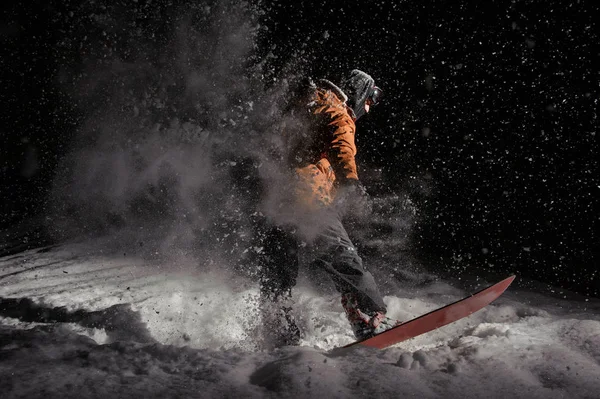 男子滑雪板在运动服和面具骑在船上在雪黑色的夜晚的粉末雪 — 图库照片