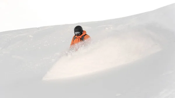 专业滑雪板在橙色运动服骑下粉山斜坡对明亮的白色天空 — 图库照片