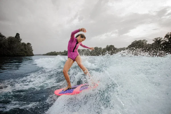 曇りの日に乗って青空青いしぶき川をピンクの水着に身を包んだ女性 Wakesurfer — ストック写真