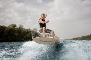 Etkin adam wakeboard Nehri arka planda gökyüzü ve ağaçlar üzerinde sağlıklı yaz sahip yüksek dalga üzerinde atlama