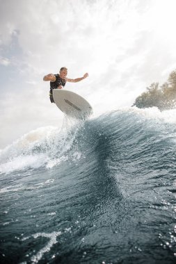 Etkin adam beyaz wakeboard gökyüzü arka plan üzerinde Nehri üzerinde sağlıklı yaz sahip Wave üzerinde atlama