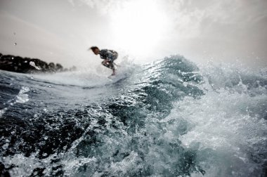 Wakeboard dalga Nehri arka planda gökyüzü ve ağaçlar üzerinde ön plan üzerinde duran aktif genç çocuk