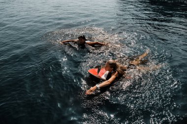 İki çekici kız wakeboards gölde yüzme siyah ve beyaz ve kırmızı mayo