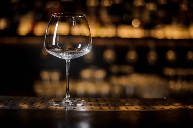 Boş şarap kadehi ayakta çubuğundaki sayaç üzerinde koyu ve sarı ışık arka plan bulanık