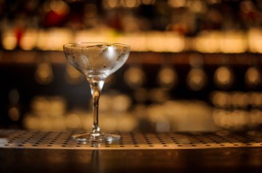 Boş çelik kokteyl cam ayakta tezgaha koyu ve sarı ışık arka plan bulanık bar