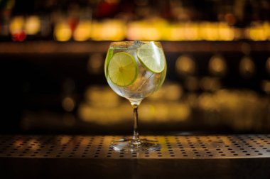 Lezzetli cin tonik kokteyl dekore edilmiş limonlu dilimler çelik çubuk üzerinde duran counter üzerinde arka plan bulanık