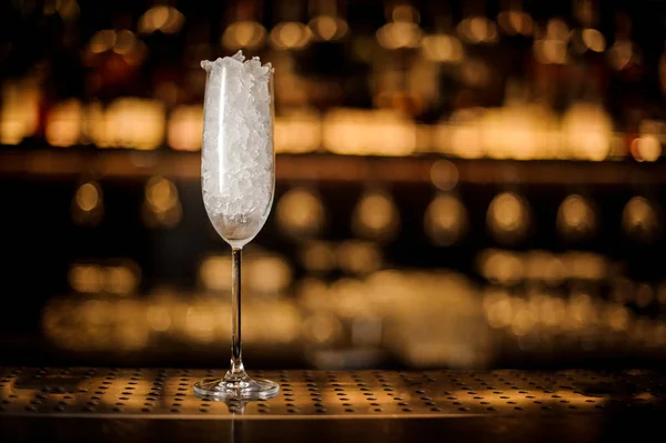 エレガントなシャンパン フルート グラスがバーに氷で満ちている明るい黄金色のライトに対してカウンター — ストック写真