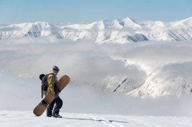 Gürcistan'daki popüler turistik tatil dağda kahverengi snowboard ile yürüyen adam