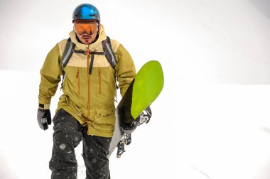 Dağ popüler turistik tatil Gürcistan'daki siyah ve yeşil snowboard ile yürüyen adam
