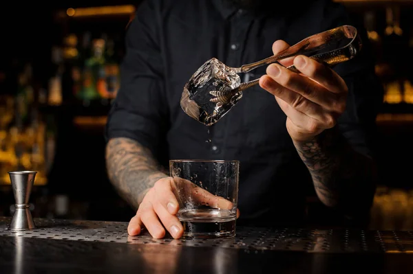 Mezclador Tatuado Poniendo Cubo Hielo Una Copa Cóctel Usando Pinzas — Foto de Stock