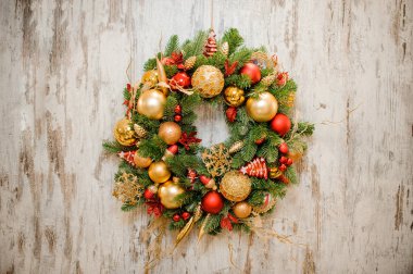 Noel çelenk kırmızı ve altın ampuller ile dekore edilmiştir.