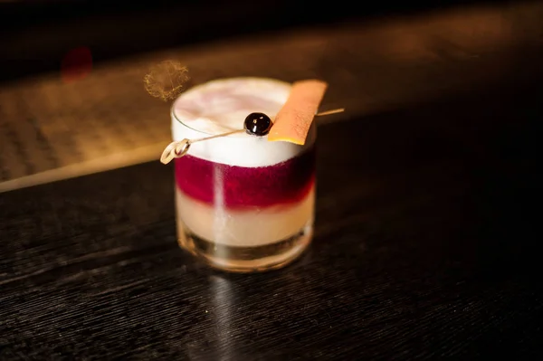 Glas mit bunten flockigen süßen und leckeren Cocktails mit Kirsch- und Orangenschalen an der Bar — Stockfoto