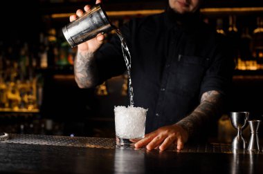 Barmen çubuğunda ezilmiş buz cam çelik shaker dan bir içecek dökülen sayaç