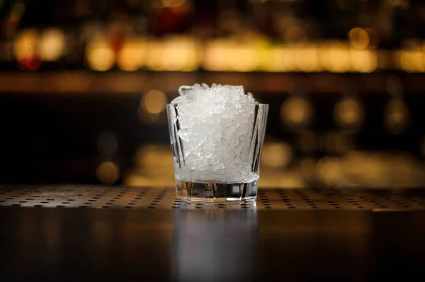 低カクテル グラスは バーのアイス キューブでいっぱいライトの背景をぼかした写真に対してレストランのカウンター — ストック写真