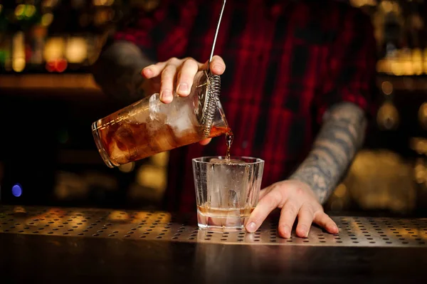 Barman vertiendo alcohol fuerte en una copa de cóctel usando colador — Foto de Stock