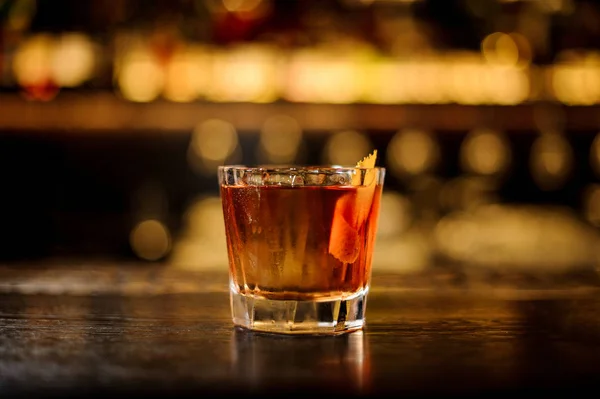 Elegant glass filled with strong cocktail with whiskey on the bar against the lights — Stock Photo, Image