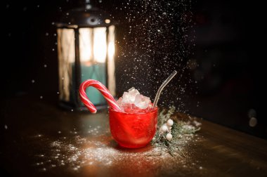 Kırmızı Kupası decorared mum kar altında arka plan bulanık üzerinde ahşap masa üzerinde köknar ağacı dalı yakınındaki şeker ile lezzetli Noel cocktal.