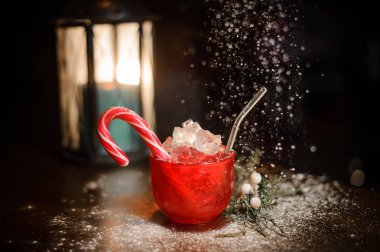 Kırmızı Kupası decorared yıldırım mum köknar ağacı dalı bulanık arka plan üzerinde ahşap masa üzerinde yakınındaki şeker ile lezzetli Noel cocktal