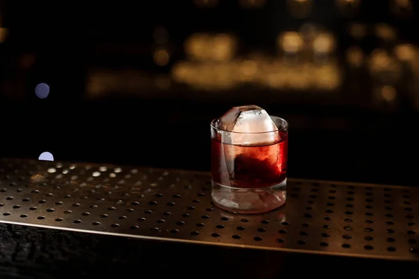 Glass of a Boulevardier cocktail on the steel wooden bar counter