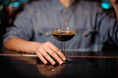 Kadın barmen çubuğu'nda bir kokteyl cam ile kahverengi alkol ayakta tutan sayaç