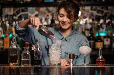 Gülümseyen kadın barmen ölçüm cam fincan bir buz küpleri kürekle ekleme.