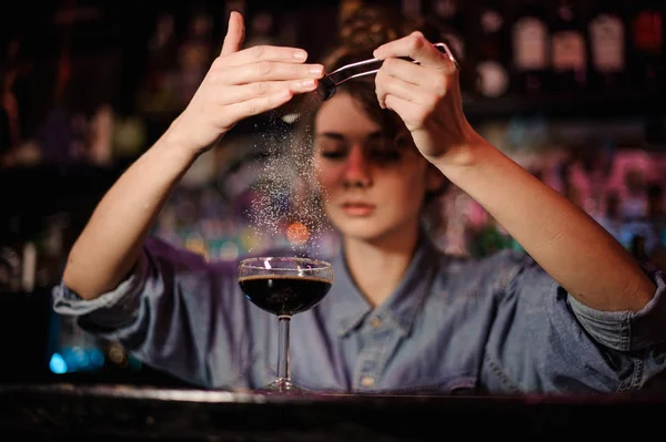 Barman feminino adicionando a um coquetel marrom um pó através do filtro no balcão da barra — Fotografia de Stock